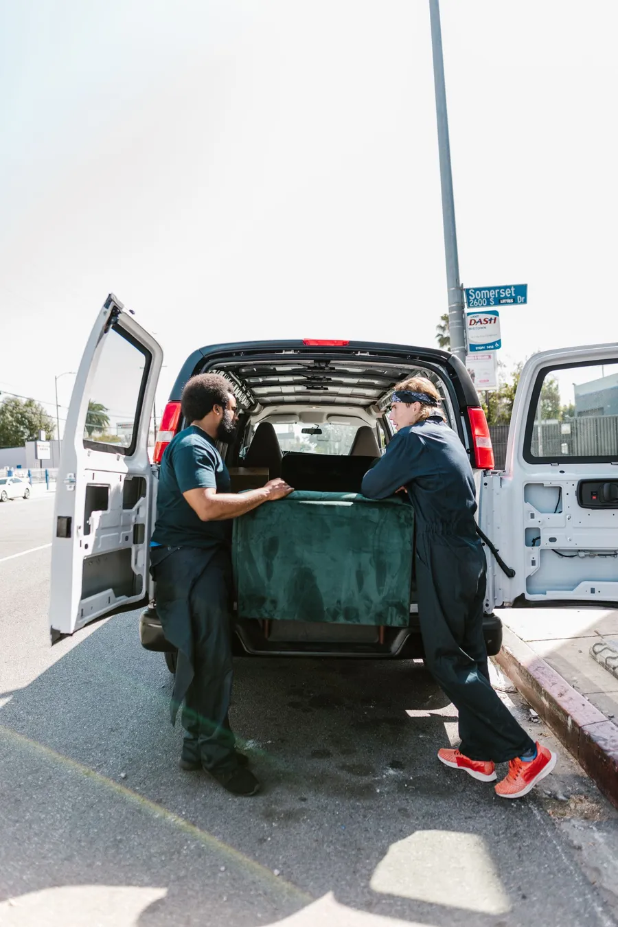 Two movers loading furniture into a delivery van