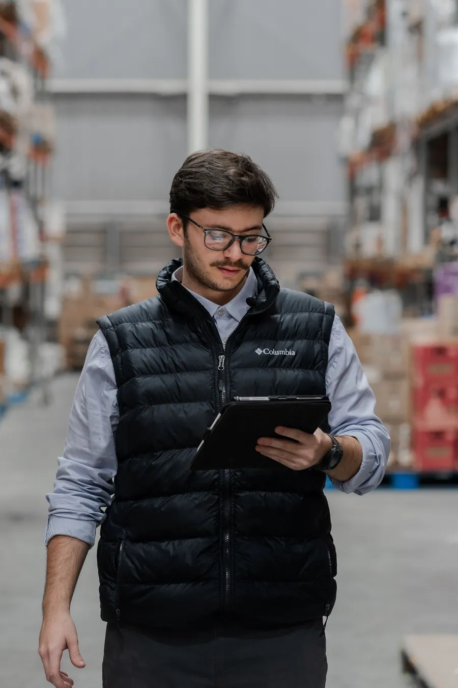 Logistics coordinator tracking inventory on a tablet in a warehouse