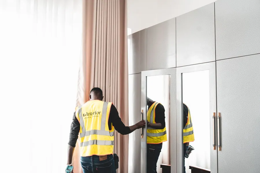 Two workers in safety vests inspecting a wardrobe for damage